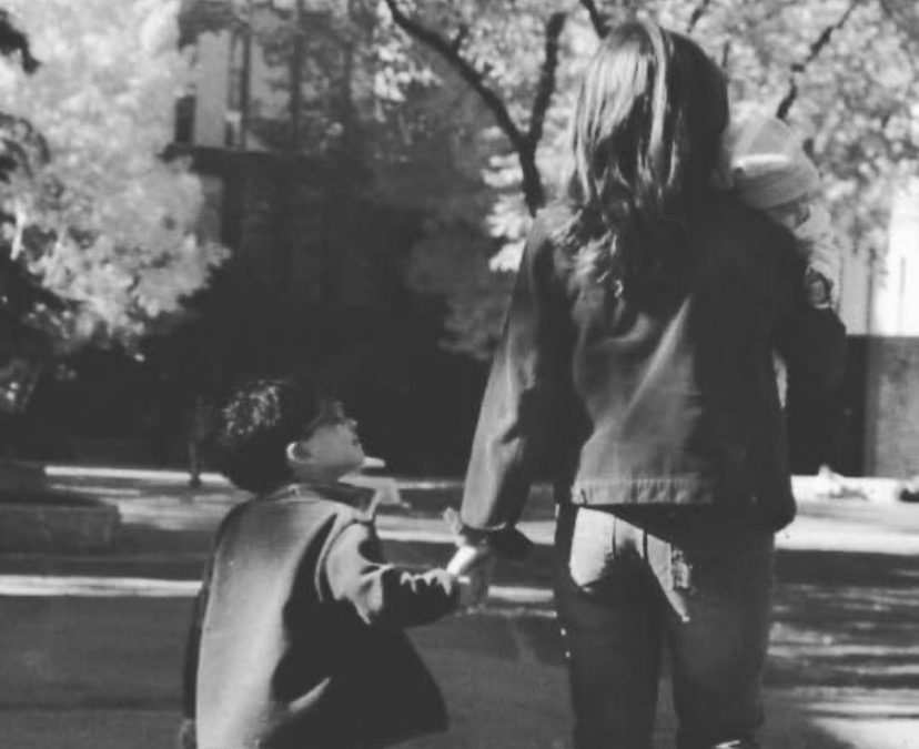 A young boy and girl holding hands on the sidewalk.